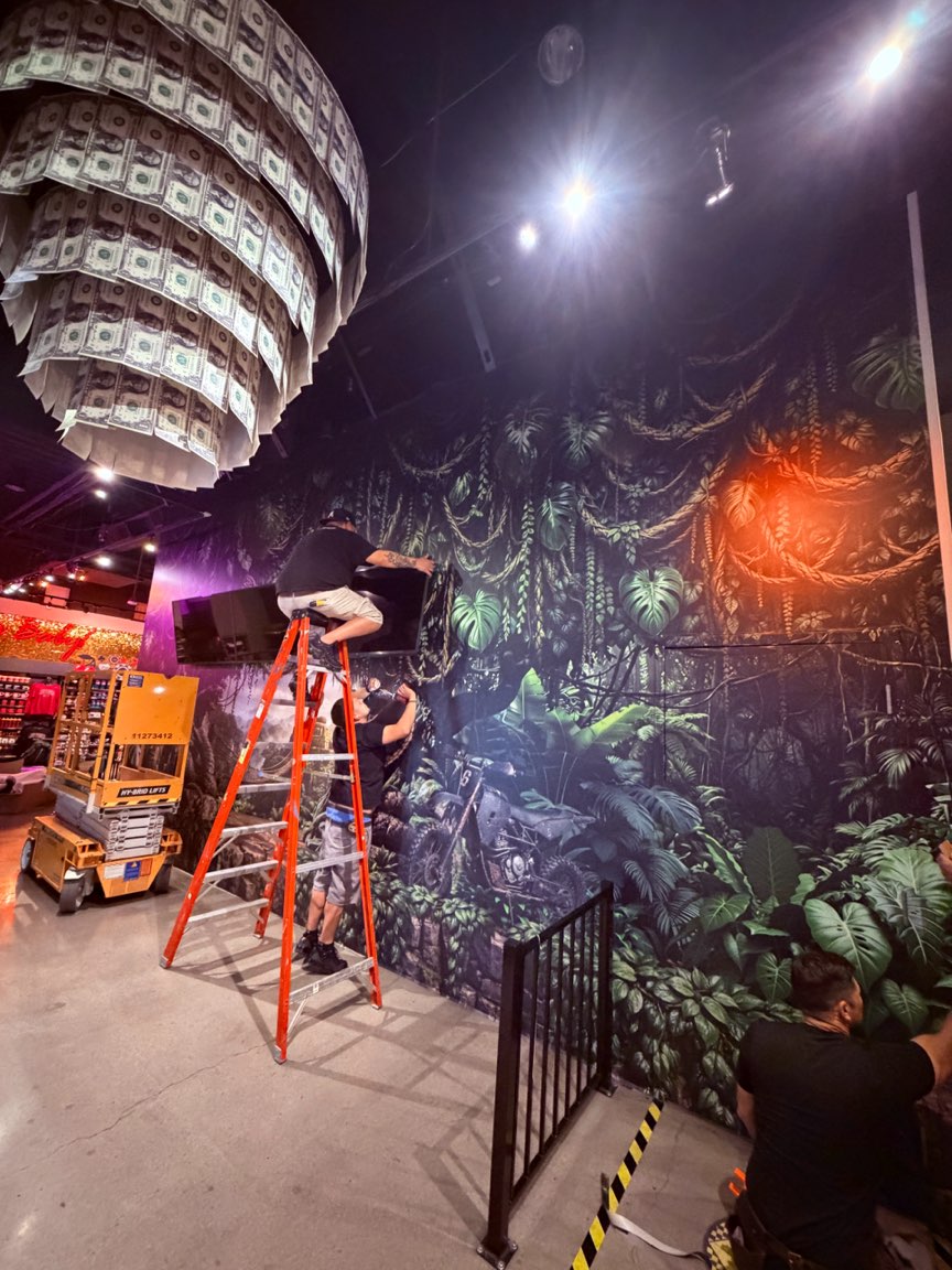 Wrap It installers hanging a jungle wall mural from a ladder