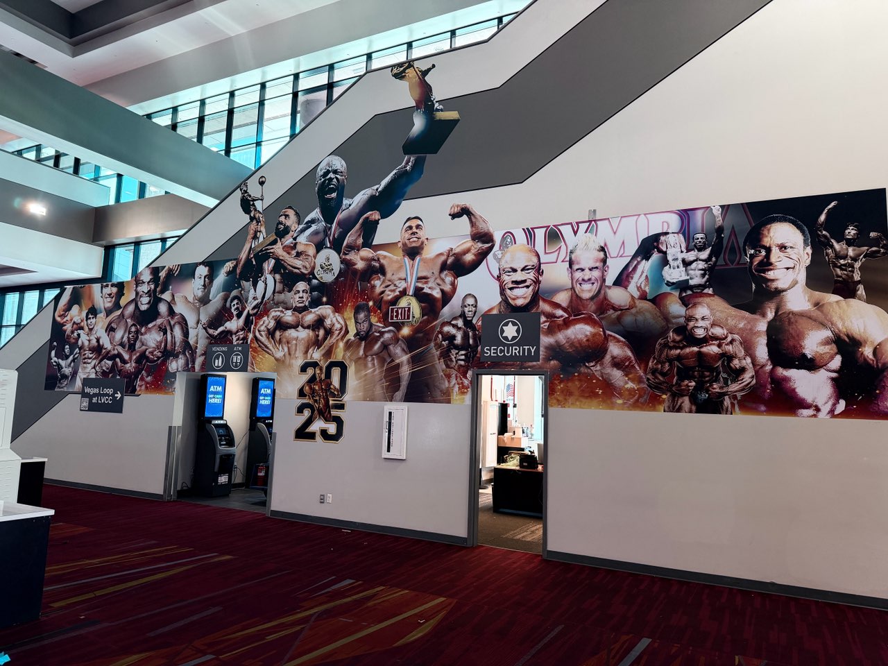Mr. Olympia 2025 bodybuilder mural installed along a convention center stairway